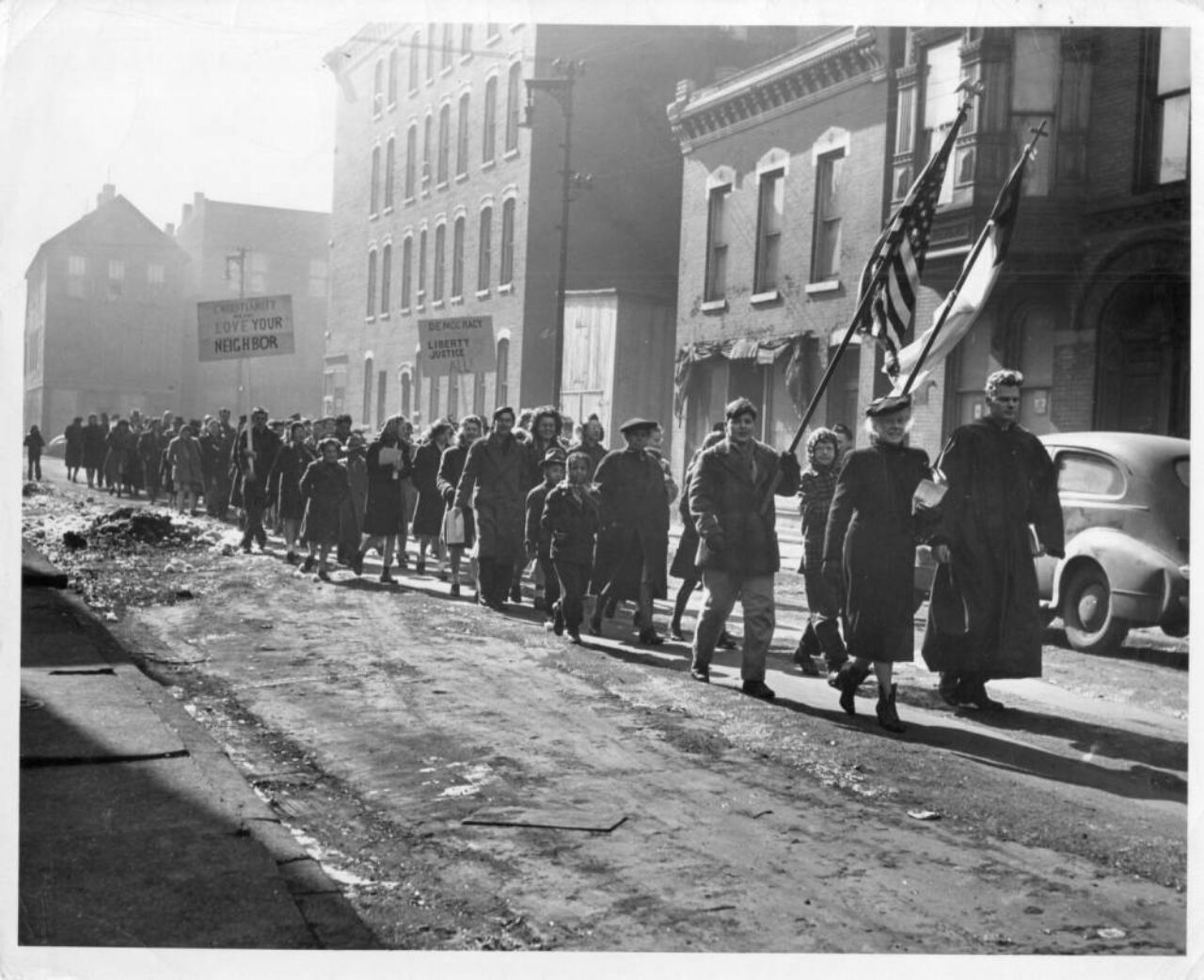 Pastor leads protest march down street holding flag