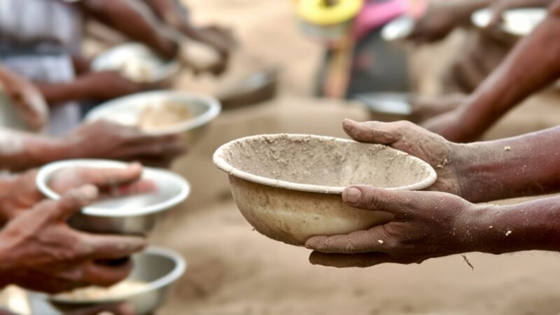 many hands hold out empty bowls for food
