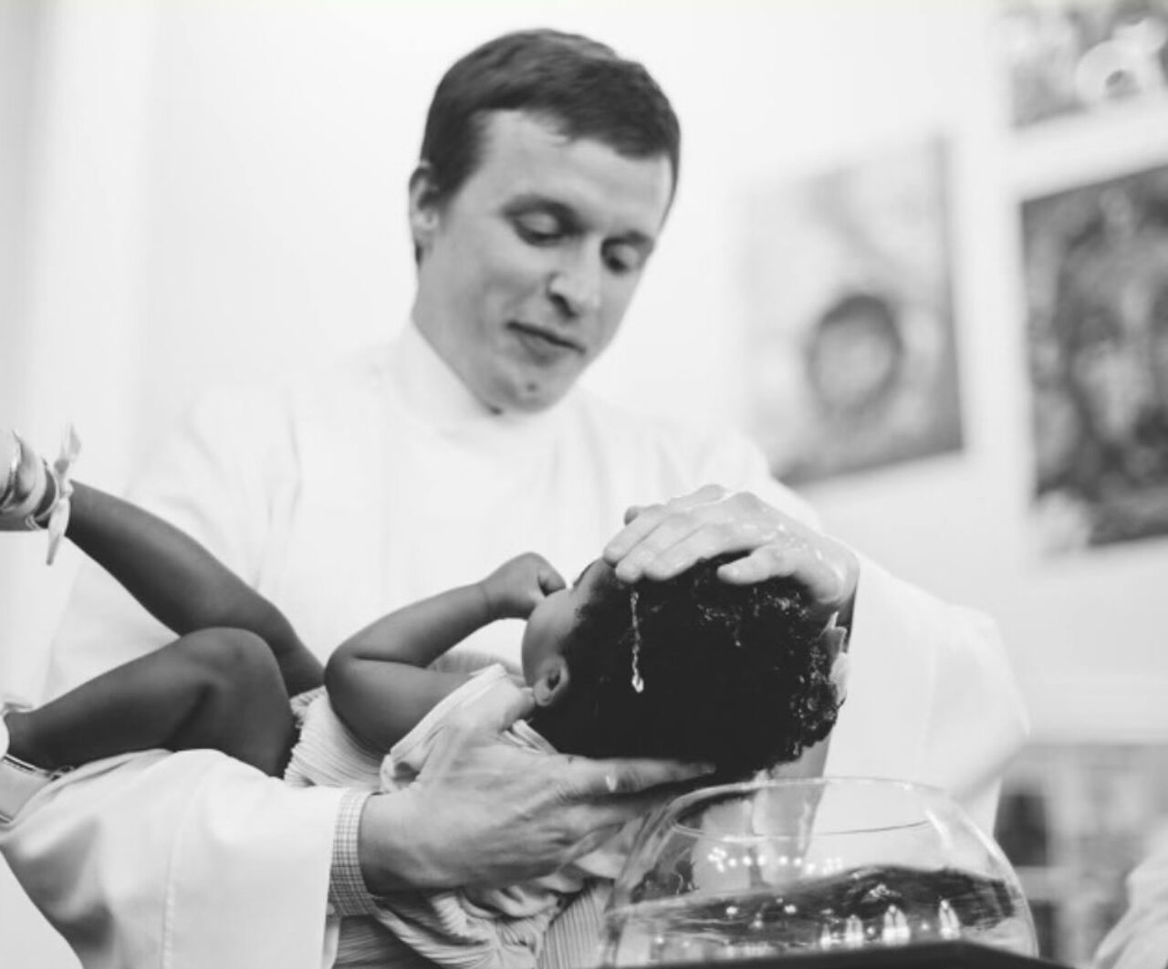 NPTS Professor Dave Bjorlin wearing liturgical clothes baptizing a baby