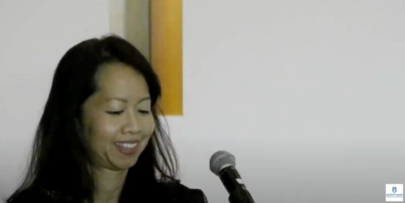 Lecturer smiles as she delivers a presentation to audience