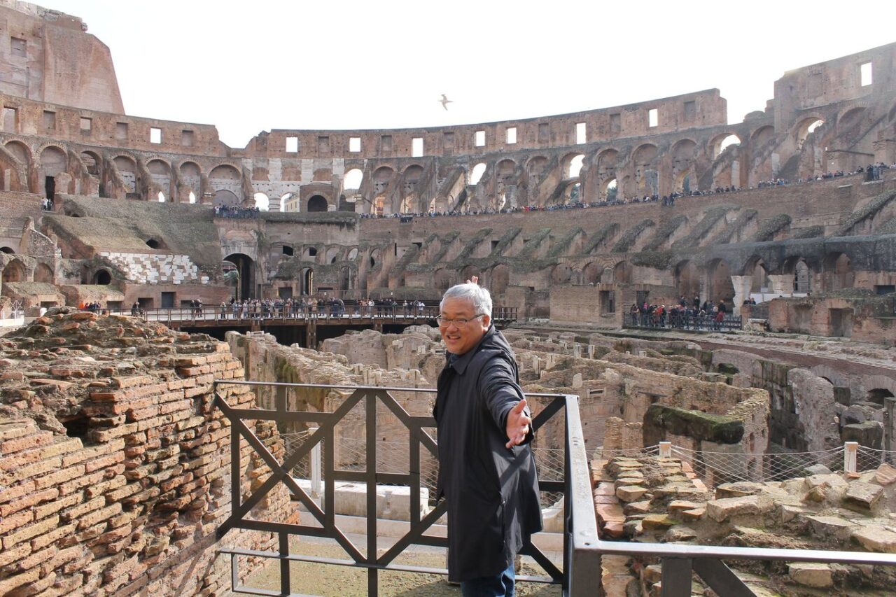 Asian American stands in the ruins of the Colosseum in Rome