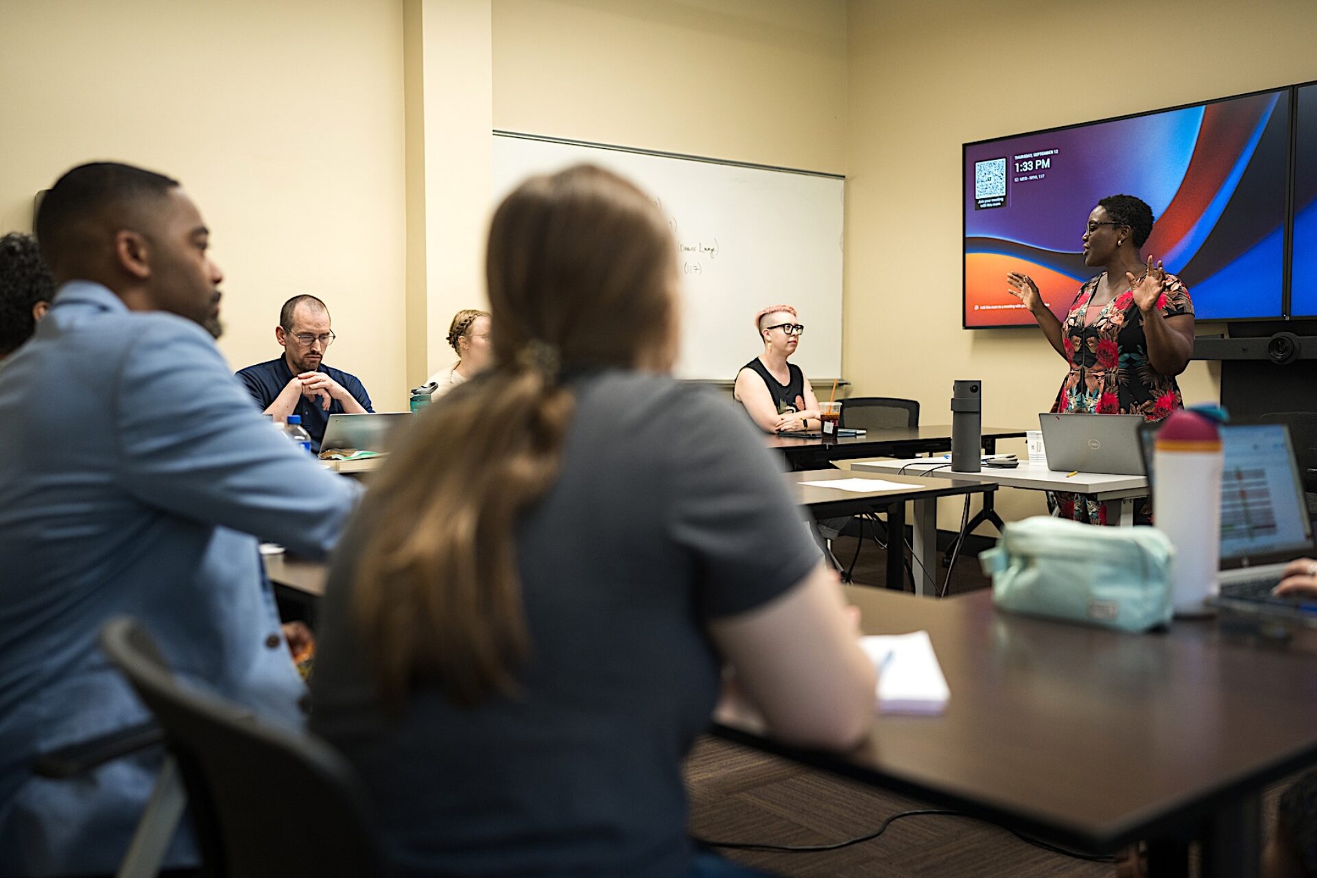 Professor teaches in front of classroom with smart screen and camera digital classroom equipment