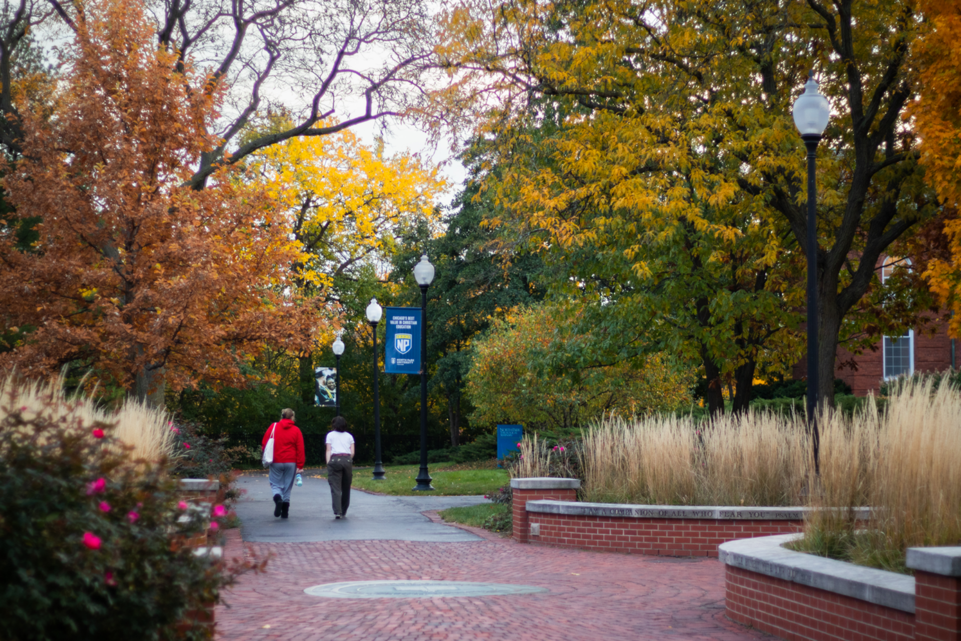 Fall with bricked walks, pair walks down middle of campus near Nyvall Hall