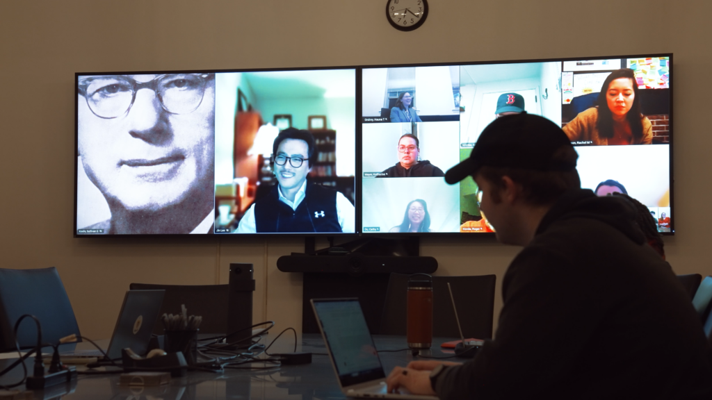students meet online on two large tv screens