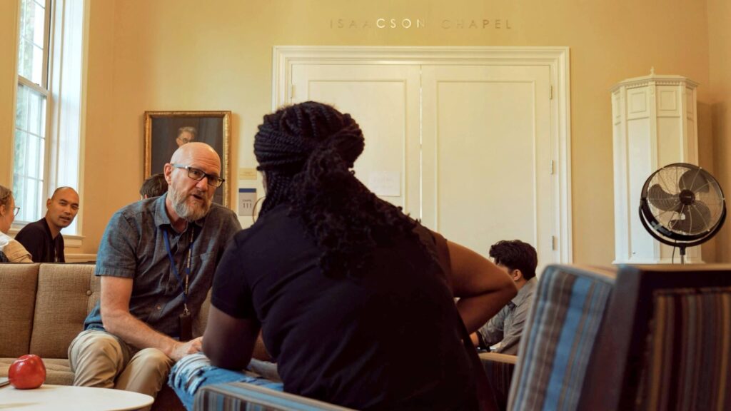 Professor talks with student on a couch