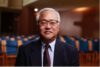Professor Max Lee stands in suit for official photo