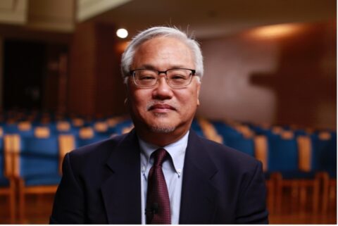 Professor Max Lee stands in suit for official photo