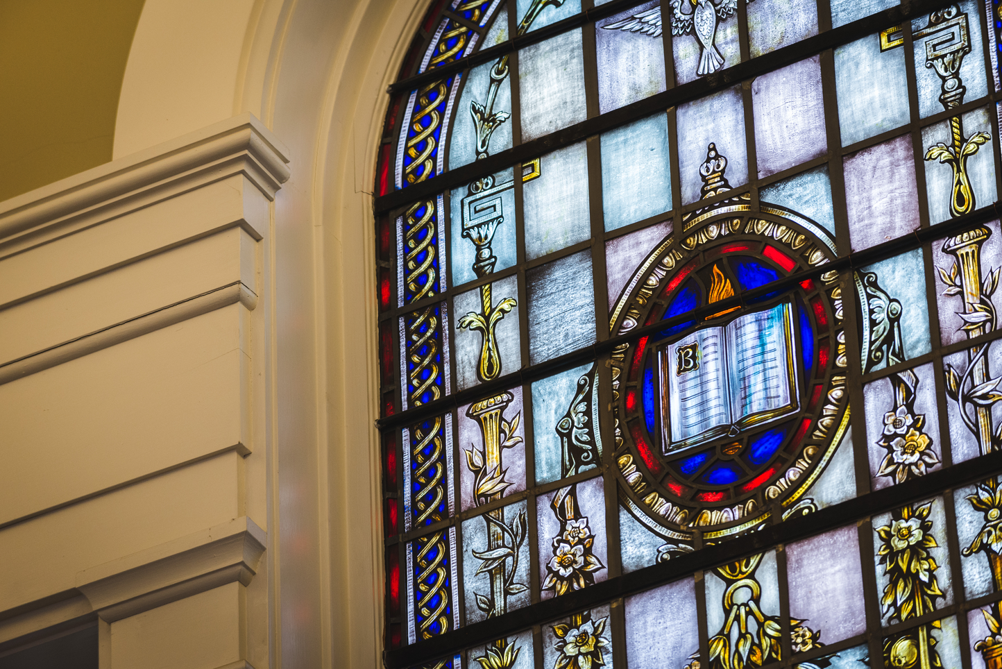 Stained glass in Isaacson chapel displays a picture of the Bible and flame