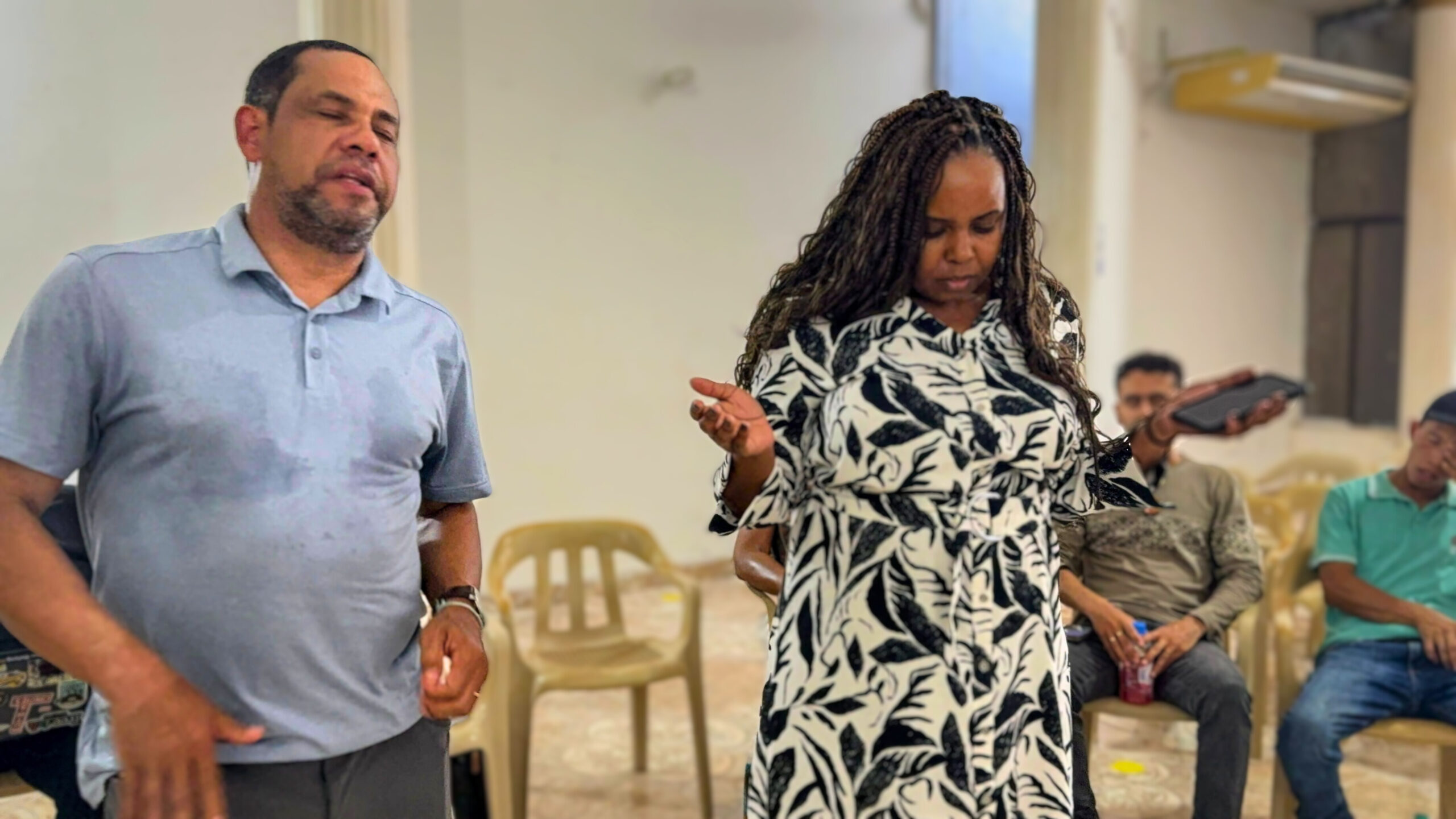 American woman holding hands in prayer with south american man also praying