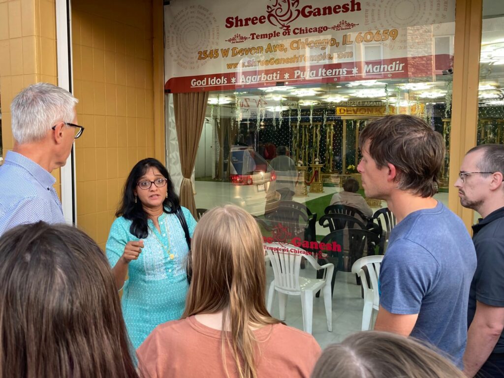 woman in traditional indian dress speaks to group of students at Shree Ganesh temple of chicago