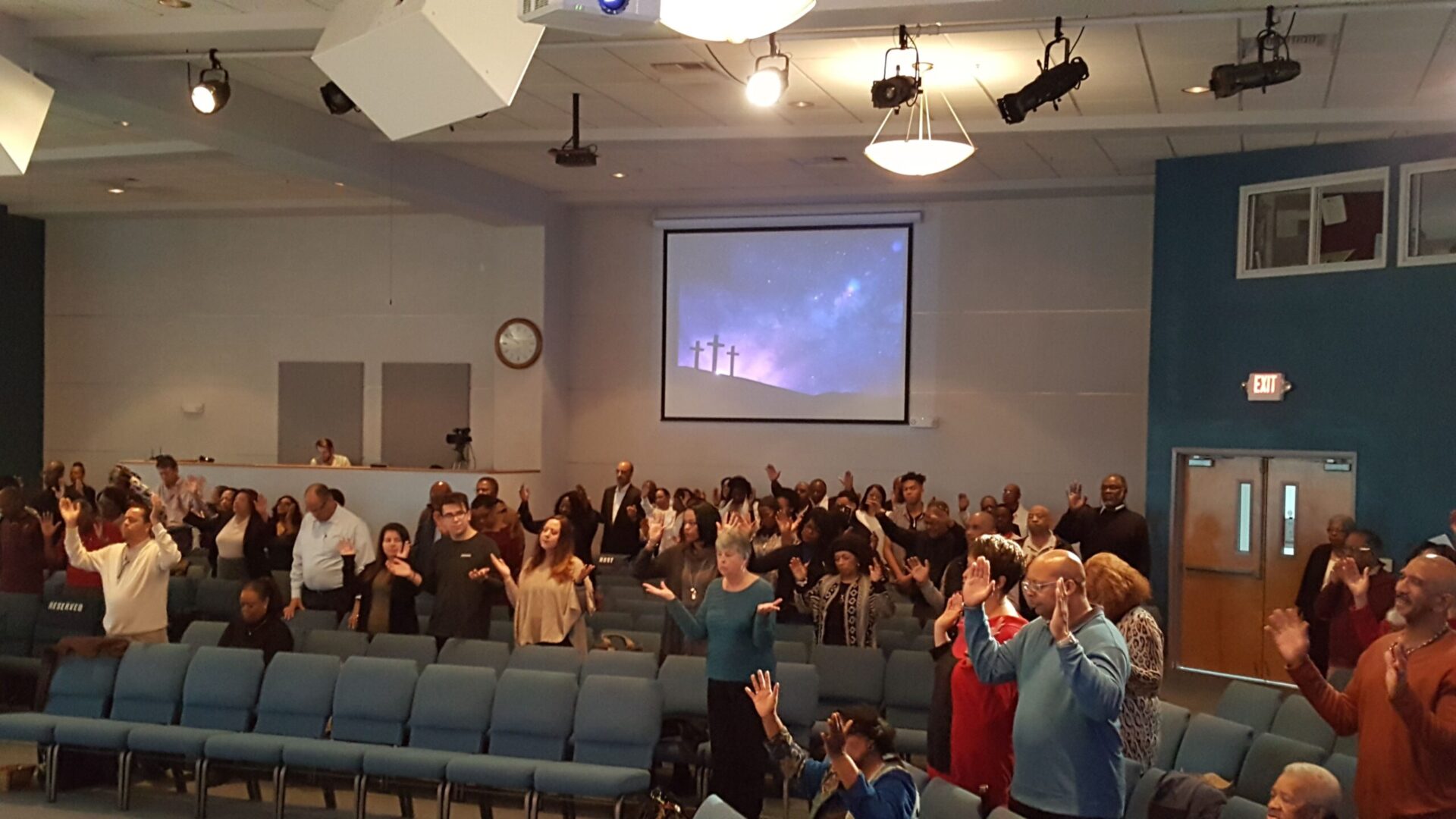 Congregants in South Bay Community Church in California in church service with hands raised in worship