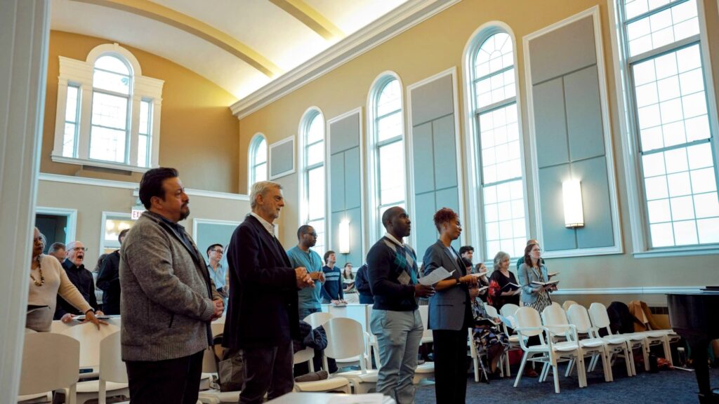 students and professors stand in worship in chapel