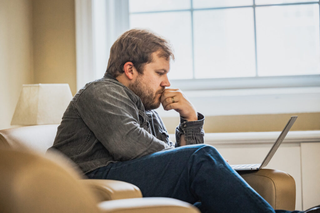 Seminary students sits in chair and studies laptop computer