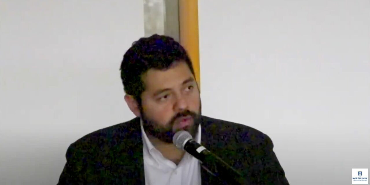 Professor speaks into microphone while looking at audience