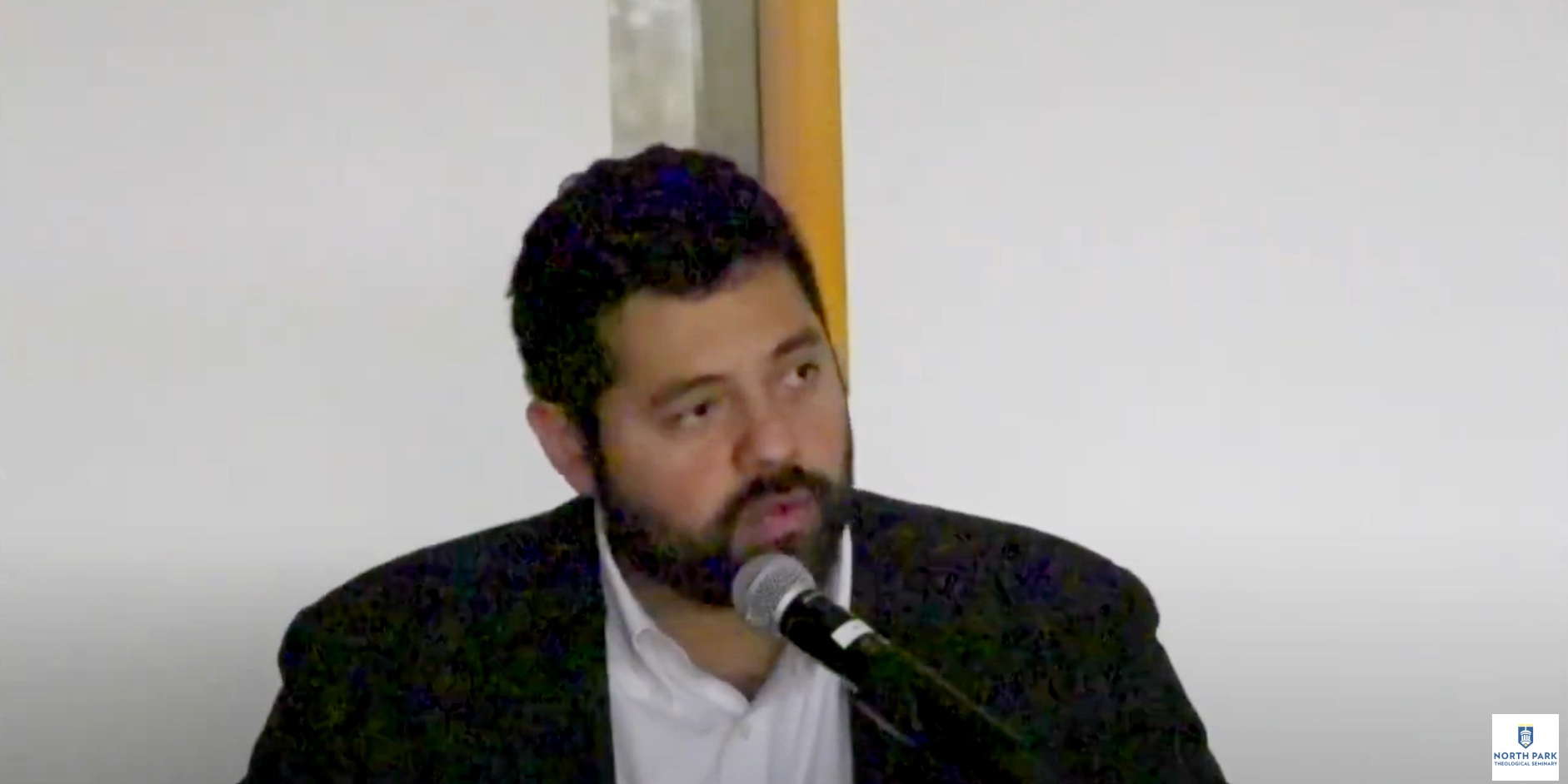 Professor speaks into microphone while looking at audience