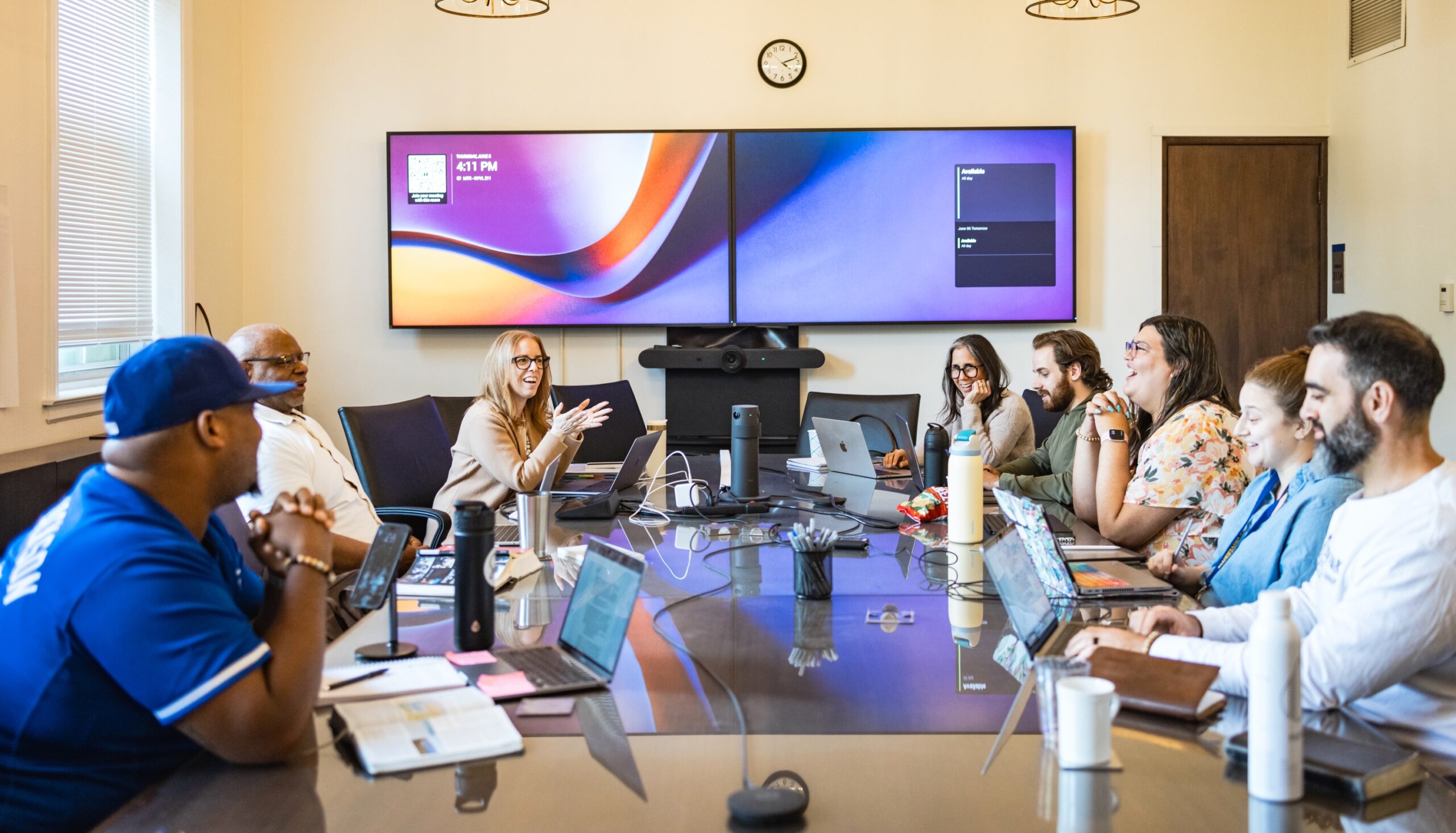 Seminary students smile in conference room class with digital screens behind them
