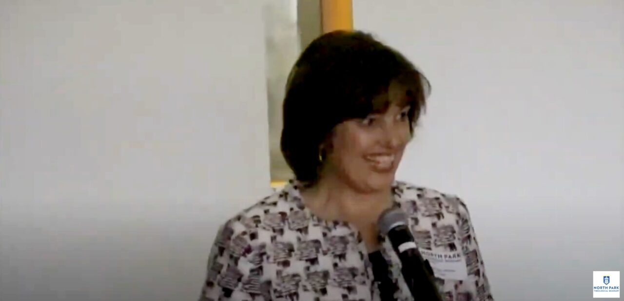 Professor smiles at the audience as she lectures