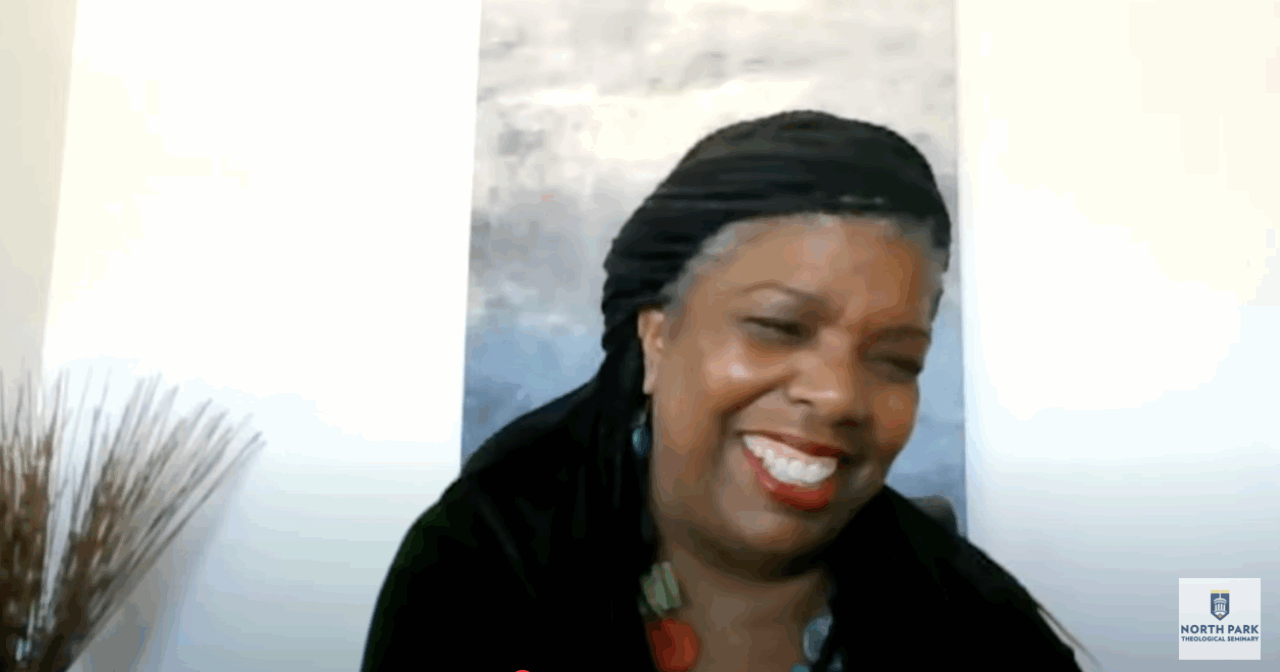 Black woman smiles at the online audience during a theological lecture