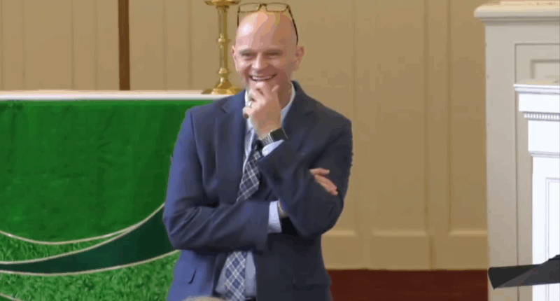 Bald man with glasses on his head and blue blazer laughs as he interacts with audience