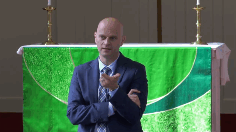 Bald man in navy suit answers audience questions in front of seminary chapel altar