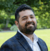 Latino man in checkered blazer smiles at the camera