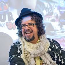 Bearded man in hat and scarf laughs in professional headshot