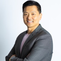 Asian man in gray blazer smiles at the camera