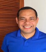 Short-haired Latino man in blue polo smiles at the camera