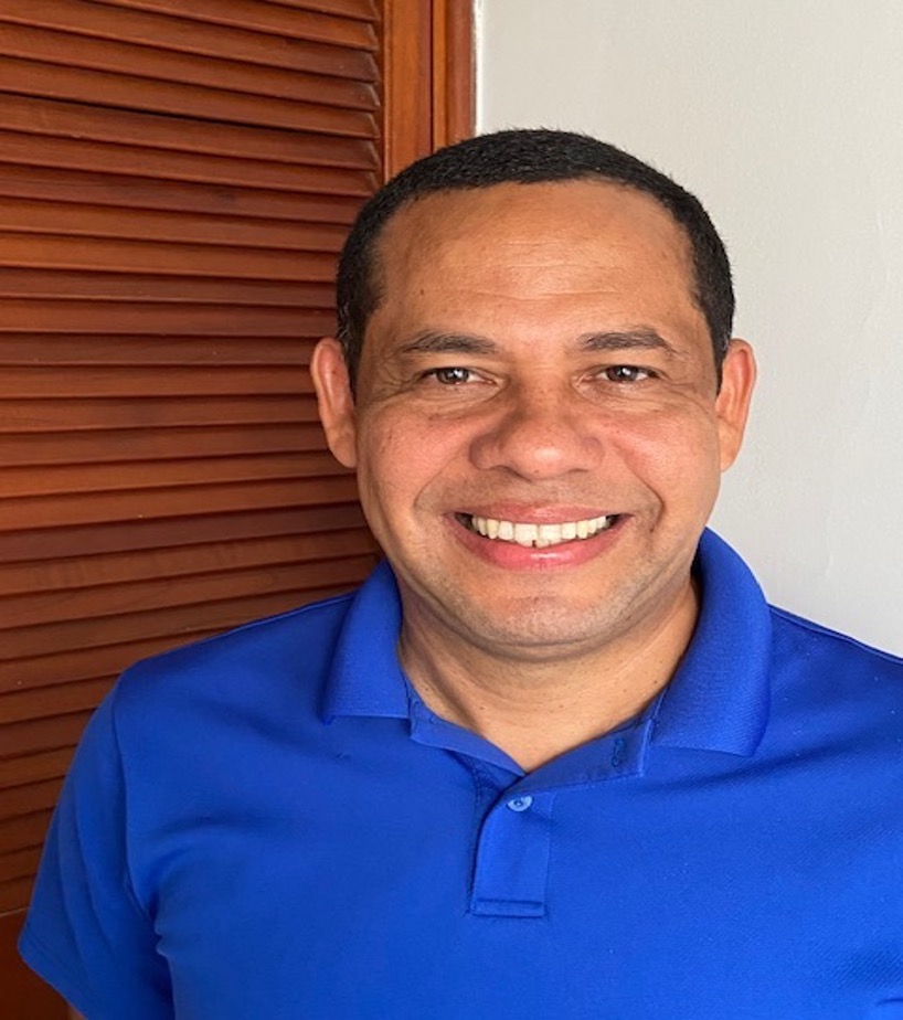 Short-haired Latino man in blue polo smiles at the camera