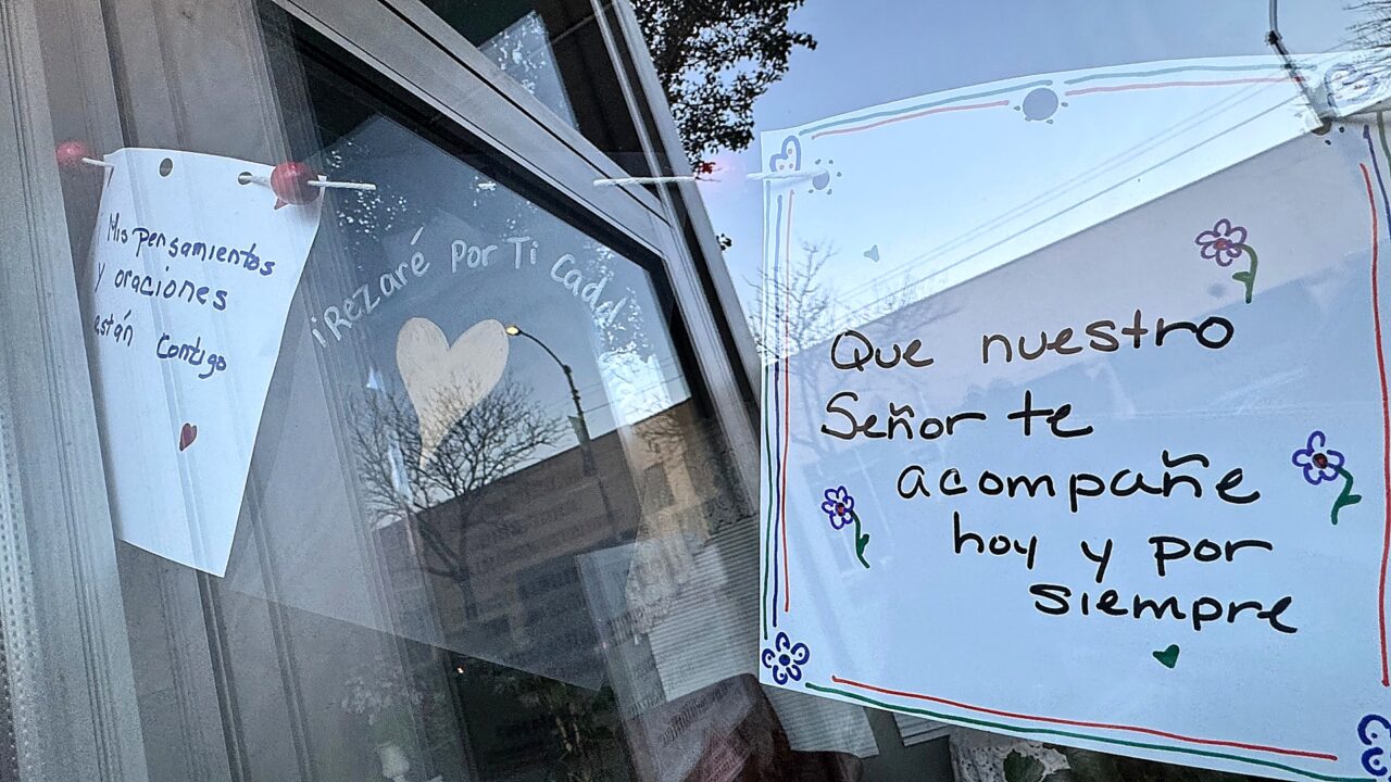 cards written in Spanish hang along a string in the storefront window of a church