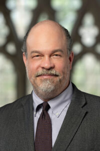 White man with white/gray goatee looks at the camera 
