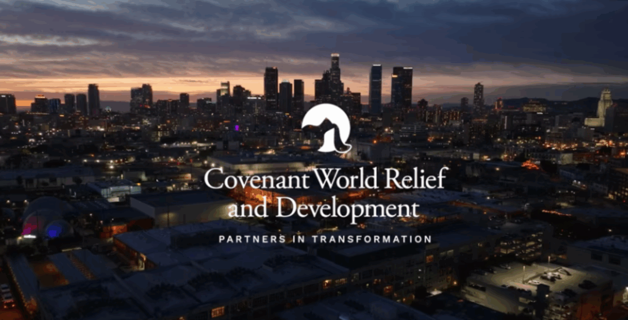 Covenant World Relief & Development logo over a photo of a city skyline at night