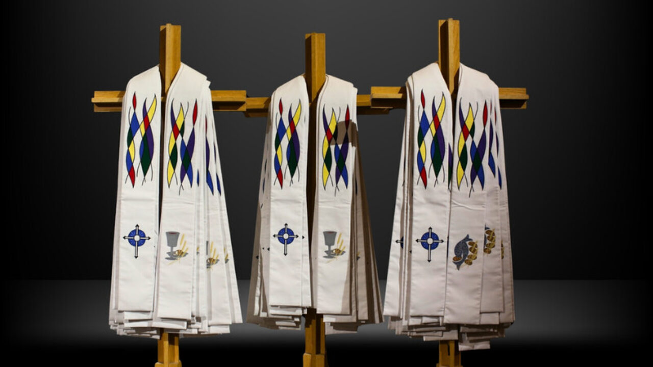 White, embroidered ordination stoles hanging on wooden crosses