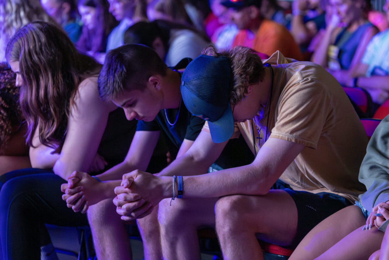 Students in prayer at large group event at Unite West