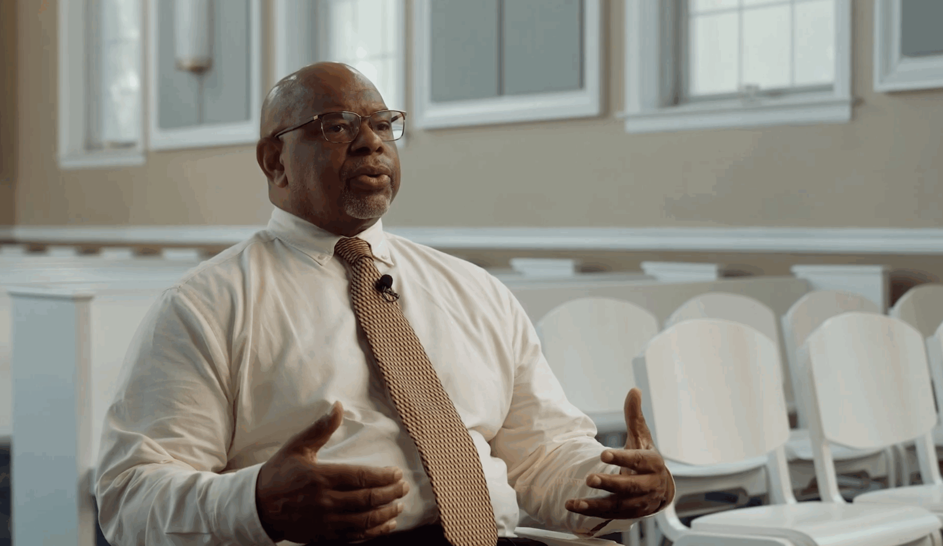 Rev. Dr. Dennis R. Edwards sitting in a chapel talking.