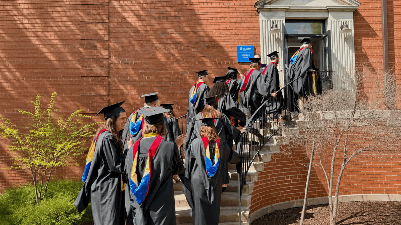color photograph of graduate processional walking up stairs into a building