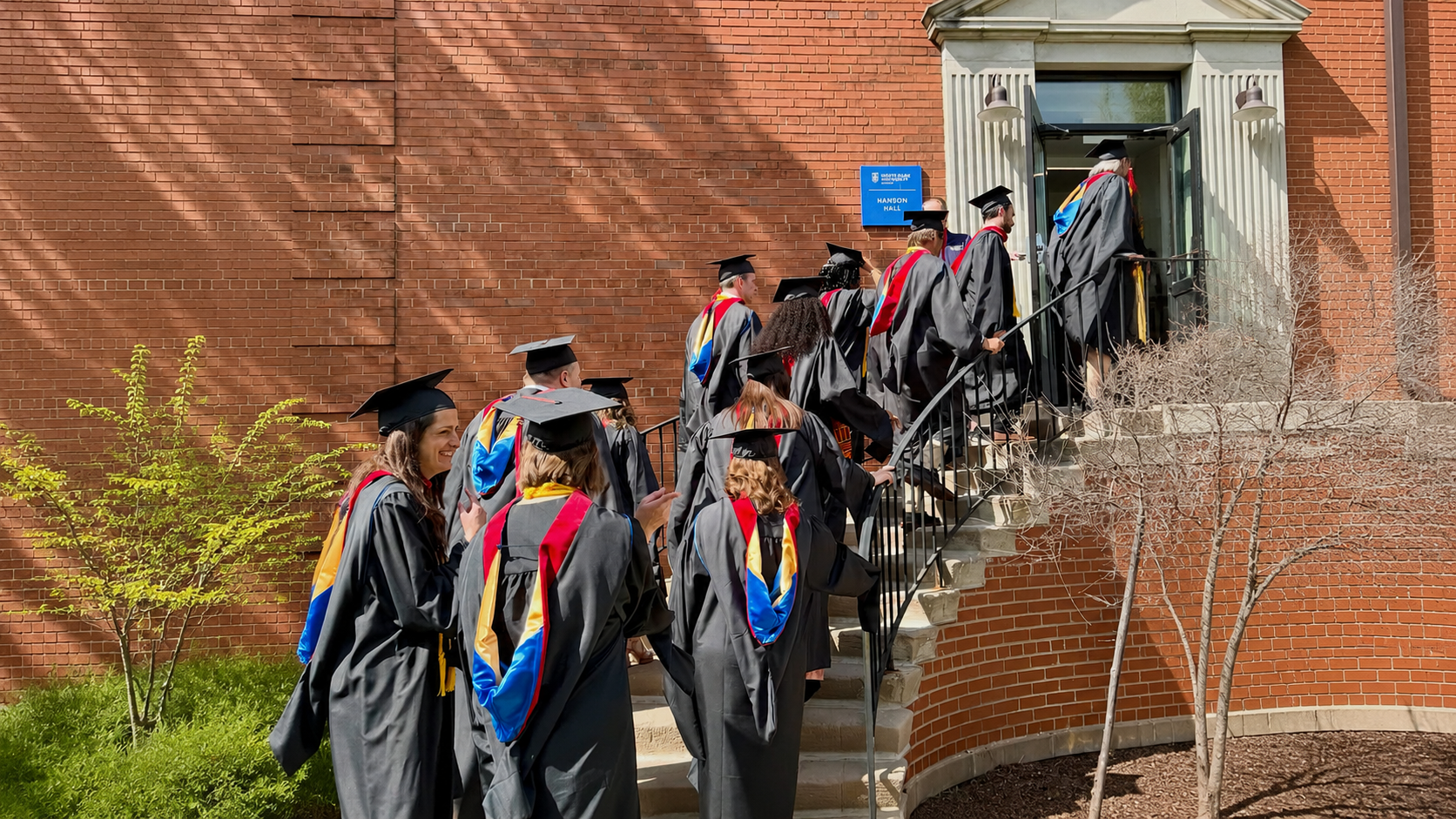 color photograph of graduate processional walking up stairs into a building