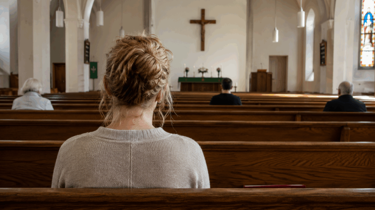 Color photograph of people sitting alone in church pews facing the altar