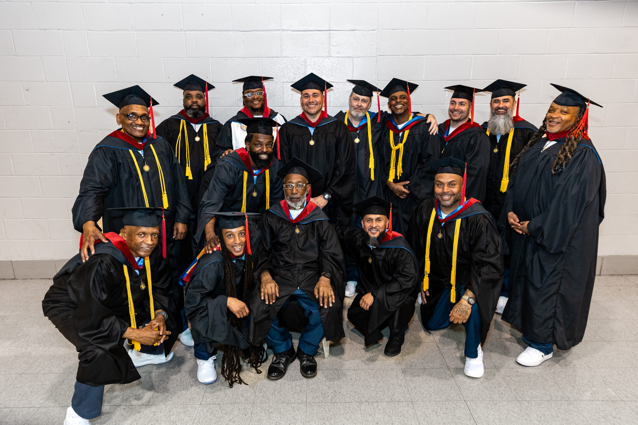 Group of male graduates in regalia smile at the camera